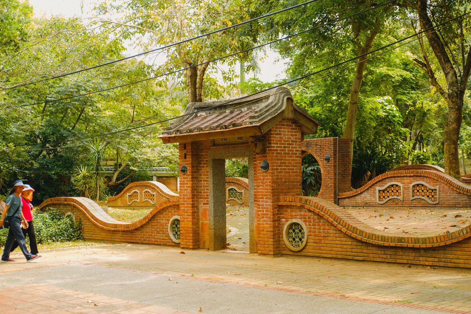 An ornate temple gateway with a sculpted, tiled wall as a visitor walks past