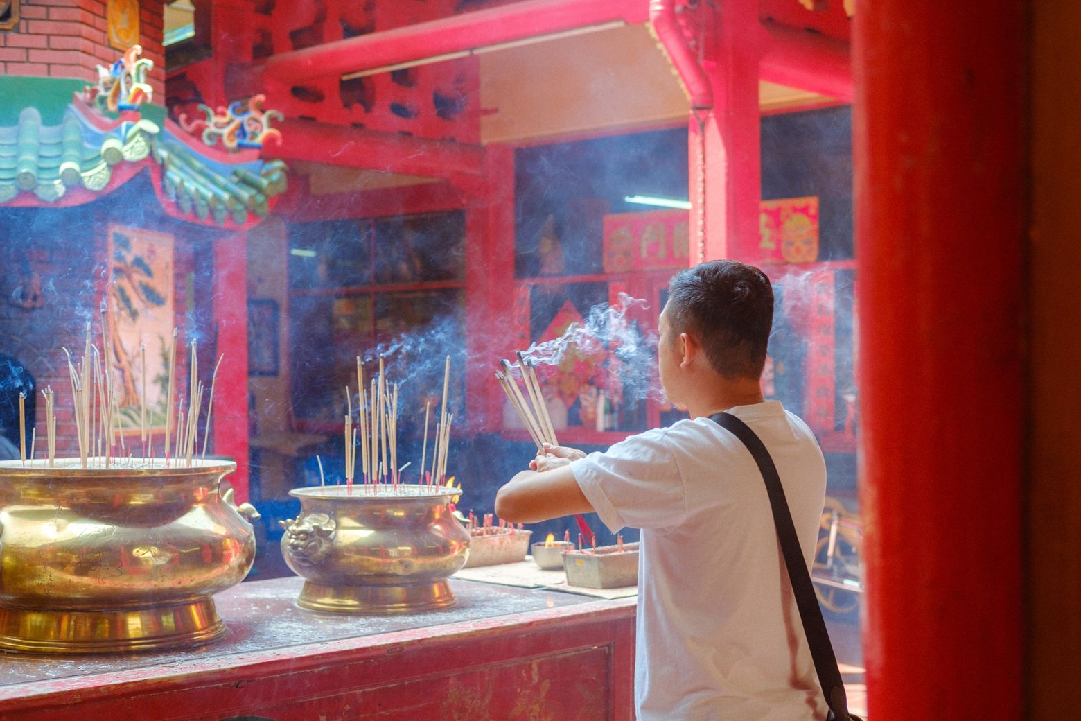 Worshippers and golden incense urns in front of a red Chinese temple