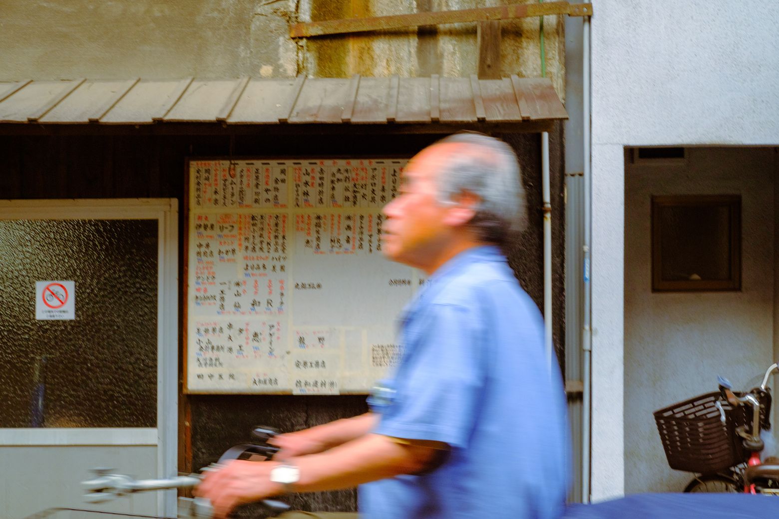 An older man in a blue shirt playing an accordion in front of a notice board
