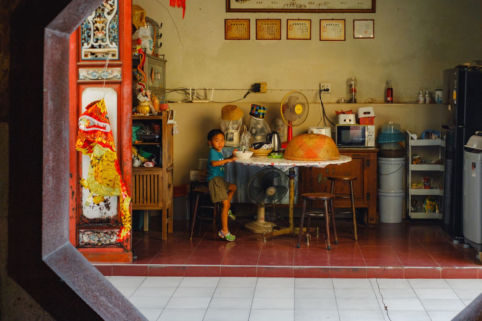 A warmly lit café interior glimpsed from the street, a customer seated at a table