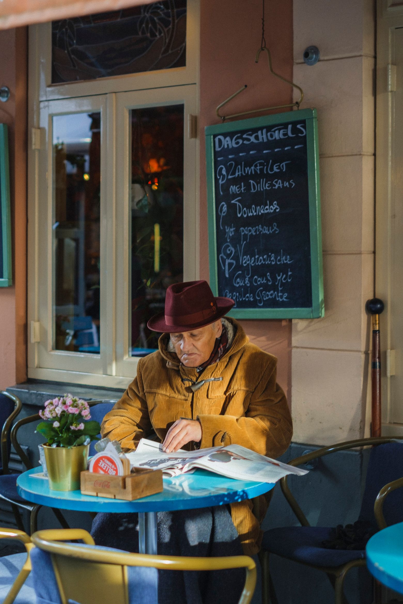 A man in a hat writing at an outdoor café table in Utrecht